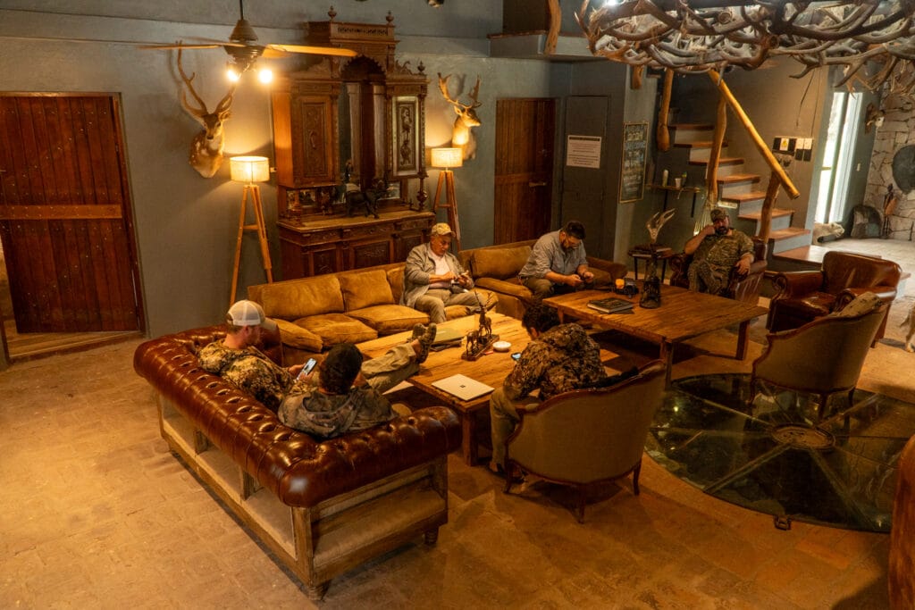 Red Stag Hunting Argentina a group of men sitting around a table in a room with antlers