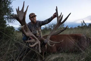 a man with a large antlers next to a large deer