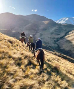 people riding horses on a hill at los andes