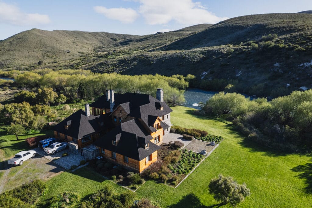 a house with a large lawn and a river in the background